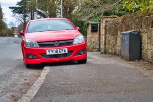 A car parks on the pavement / sidewalk, restricting space for pedestrians - taken in the UK.